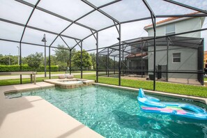A swimming pool with a glass enclosure, a hot tub, and a lounge area.