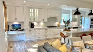 Una cocina moderna con armarios blancos, una isla central y un comedor con sofá y sillas.