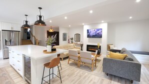 Un espacio de estar moderno con una isla central, un sofá, un sofá gris y una chimenea.
