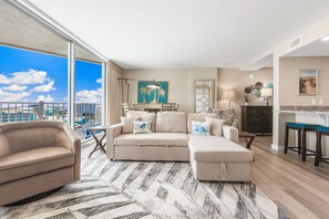 A spacious living room with a large sofa, a dining area, and a kitchen. - Sandcastle Condominiums Unit 530 (Port Aransas)