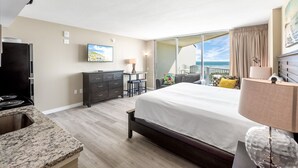 A bedroom with a large bed, a desk, a dresser, and a view of the ocean. - Sandcastle Condominiums Unit 532 (Port Aransas)