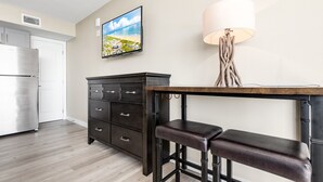 A modern kitchen with a stainless steel refrigerator, a dark wooden table with a bench, and a wall-mounted lamp. - Sandcastle Condominiums Unit 532 (Port Aransas)