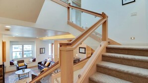 Un intérieur moderne avec un escalier en bois, un espace de vie comprenant un canapé et une table basse, et une vue à travers une porte vitrée.