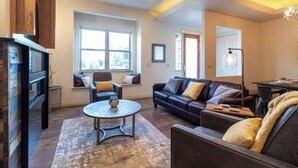 Un salon avec une cheminée, un canapé, une table basse et une fenêtre.