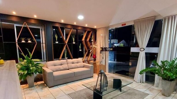 A modern living room with a sofa, a coffee table, and potted plants.