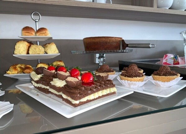 A dessert display with various cakes and pastries on a glass counter.
