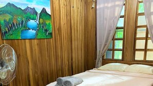 Un dormitorio con cama, ventilador y un cuadro de un paisaje.