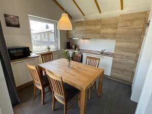 Enjoy cooking in this kitchen with a central island, stove, and sink, plus a dining area with a table and chairs.