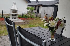 Relax in a serene outdoor space with a grill, comfortable seating, and a beautifully manicured lawn.