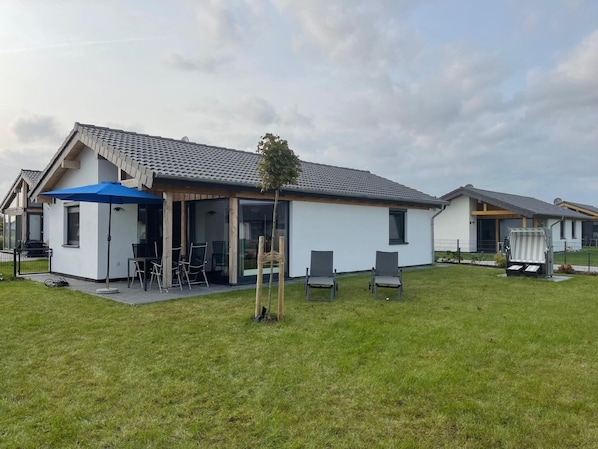 Relax in the open patio area with a comfortable dining set and lush green surroundings.