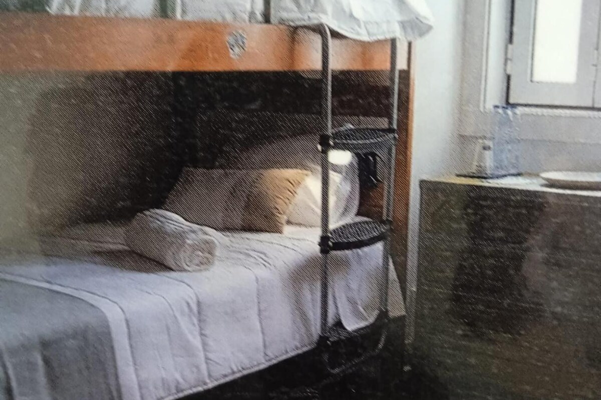A bunk bed with a headboard, a bedside table, and a chair.