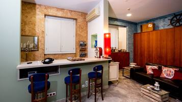 Un espacio habitable compacto con kitchenette, una barra con taburetes, un sofá y un armario de madera.