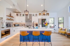 Una cocina moderna con armarios blancos, una isla grande con taburetes de bar e iluminación colgante.