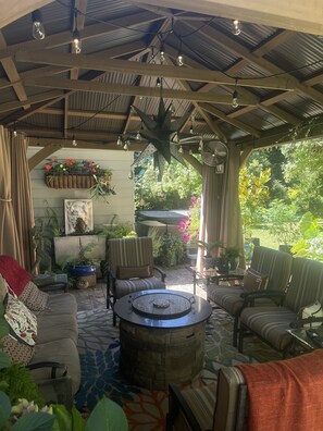 A covered patio area with seating, a fan, and potted plants.