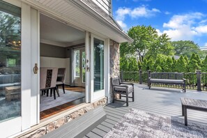 A covered outdoor deck with a stone wall, a bench, and a table. - Walk to shopping, Charming Modern European cottage with huge deck (Birmingham)