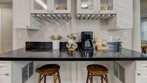 A kitchen with a central island, white cabinets, and a coffee maker.