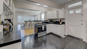A modern kitchen with a central island, black tiled flooring, white cabinetry, and a visible microwave.