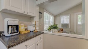 A kitchen with white cabinets, a coffee maker, a bread maker, and a plant on the counter.