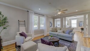 A spacious living room with a light blue sofa, white armchairs, and a coffee table.