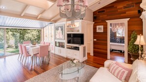 A spacious living area with a dining table, a sofa, a TV, and a chandelier.