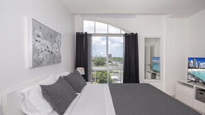 Una moderna camera d'albergo con un grande letto, un quadro, una TV e vista sulla città.