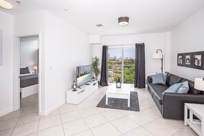 A modern living room with a flat-screen TV, a sofa, a coffee table, and a balcony with a city view. - Modern/Self Checkin/Parking/FastWIFI/PetsOk (Miami)