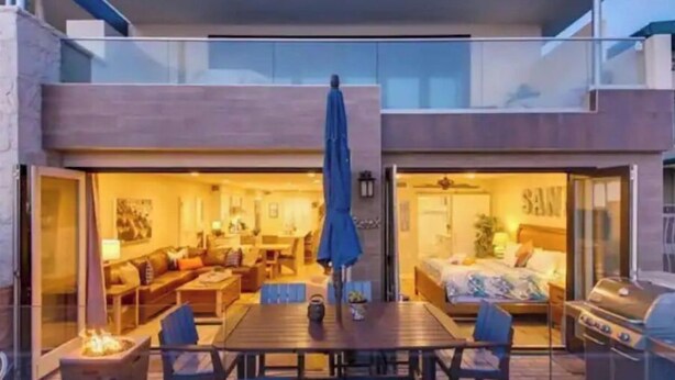 Et moderne hus med en patio, der har et spisebord, stole og en grill.