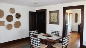 A dining area with a wooden table and checkered chairs, surrounded by woven wall hangings. - Cozy 1920s Farmhouse in the Ozark hills (Green Forest)