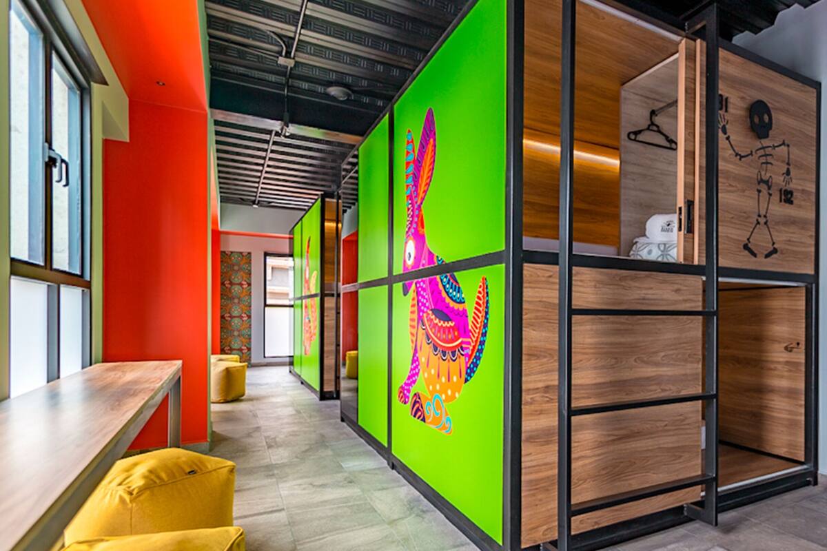 A modern office space with a vibrant green partition, wooden shelving units, and a yellow couch.