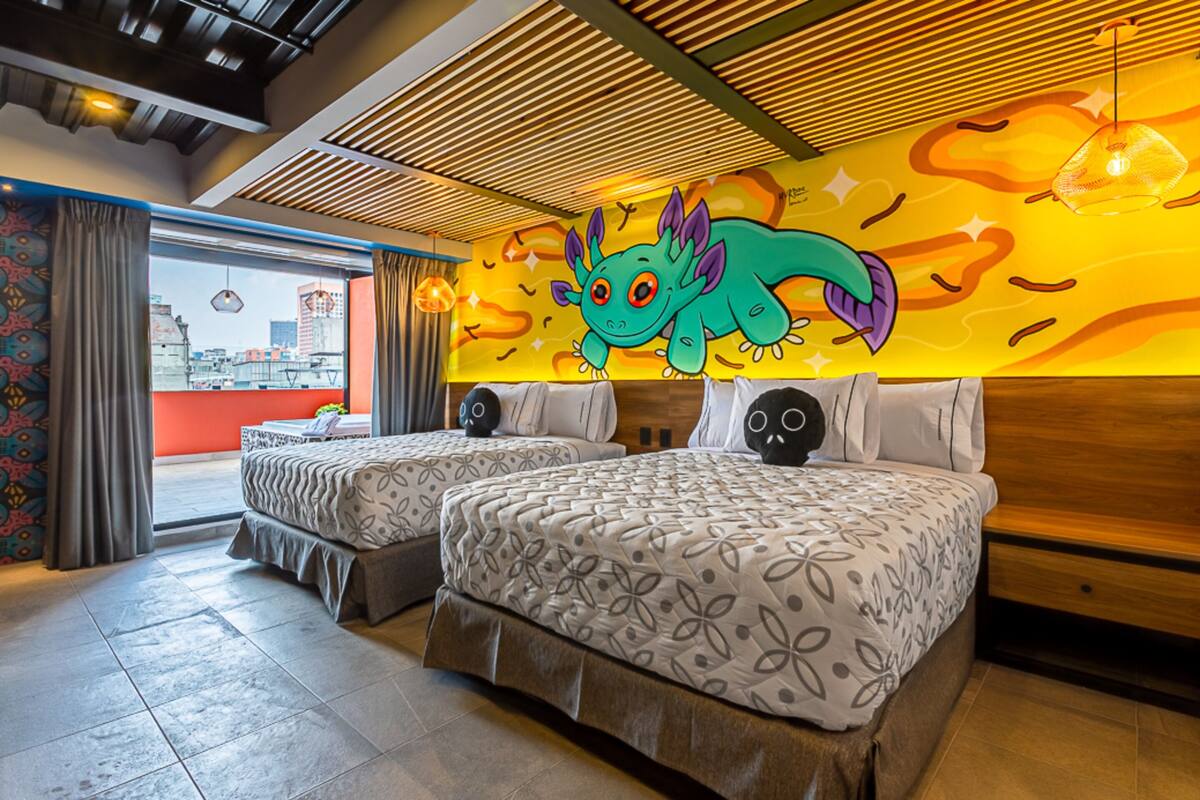 A hotel room with two beds, a city view, a mural of a cartoon monster, and a modern ceiling design.