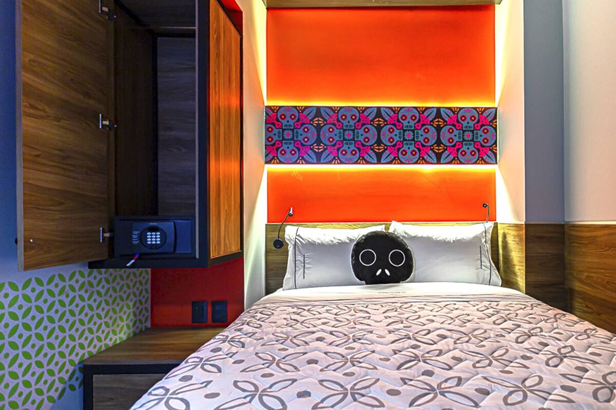 A hotel room with a bed, a nightstand, and a wall-mounted TV.