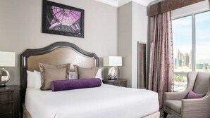 A hotel room with a large bed, a cityscape view, a framed artwork above the bed, and a chair by the window. - Charming 1 BR Vegas Resort | Pools & much more. (Kissimmee)