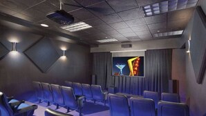 A modern cinema room with rows of black seats, a large screen, and ambient lighting. - Charming 1 BR Vegas Resort | Pools & much more. (Kissimmee)