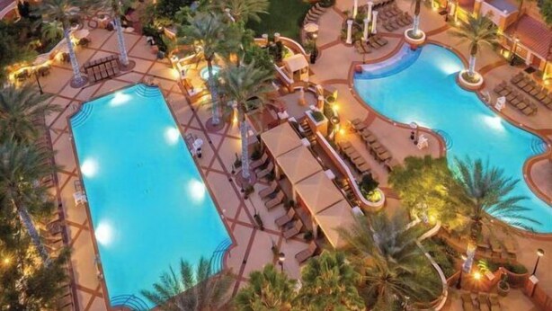 A hotel with multiple swimming pools, palm trees, and outdoor seating areas. - Charming 1 BR Vegas Resort | Pools & much more. (Kissimmee)
