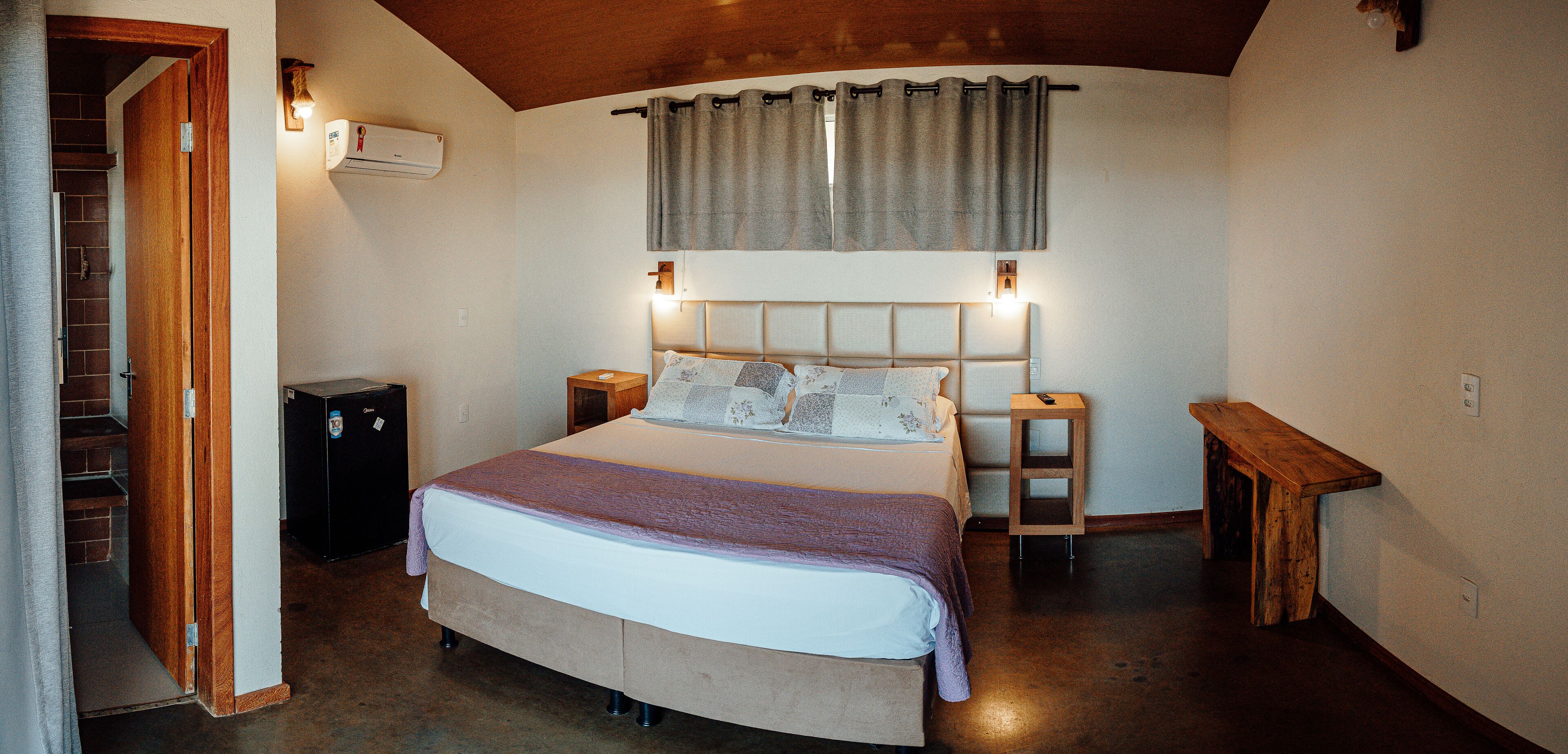 Quarto com cama, mesas de cabeceira, aquecedor e um banco de madeira.