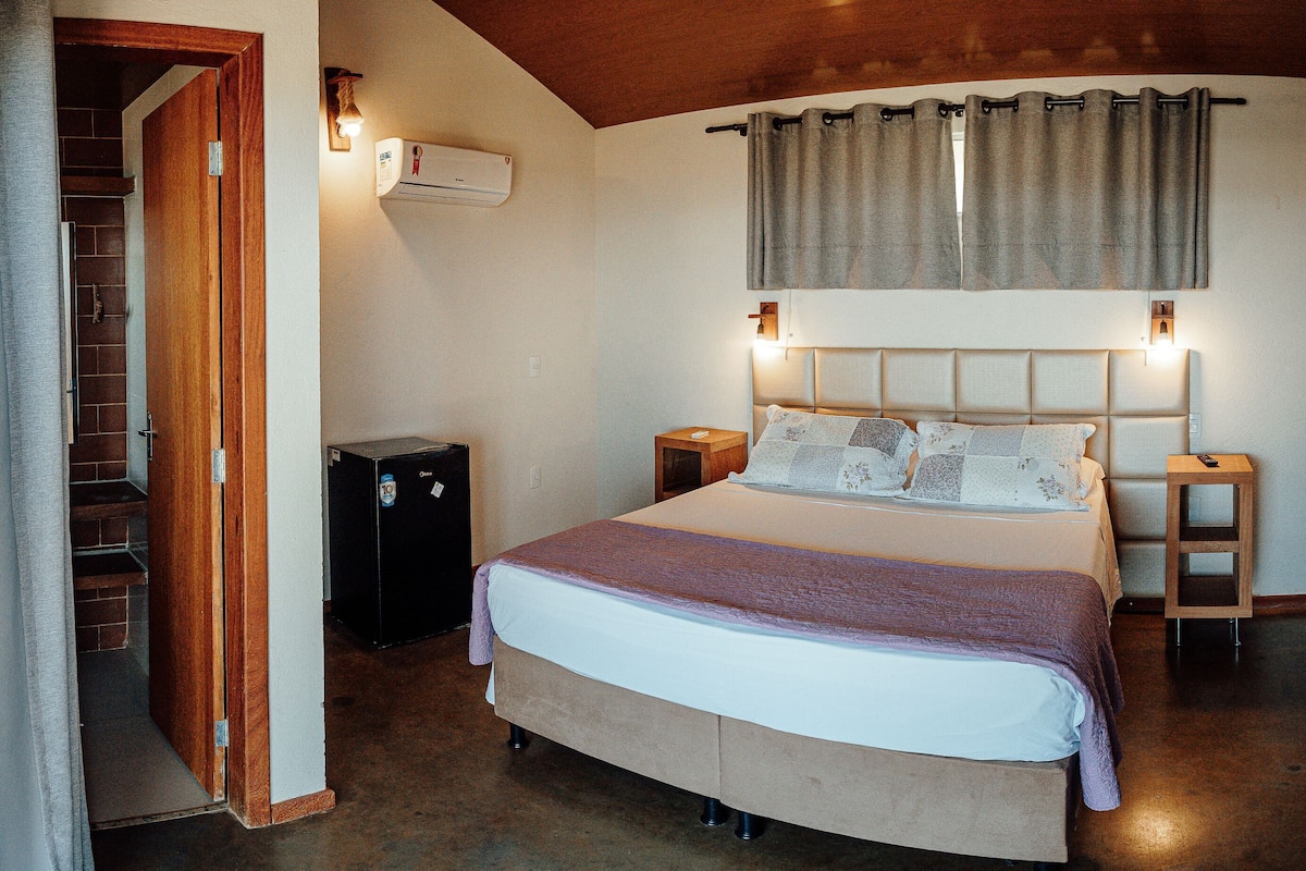 A bedroom with a bed, bedside tables, a heater, and a wooden bench.