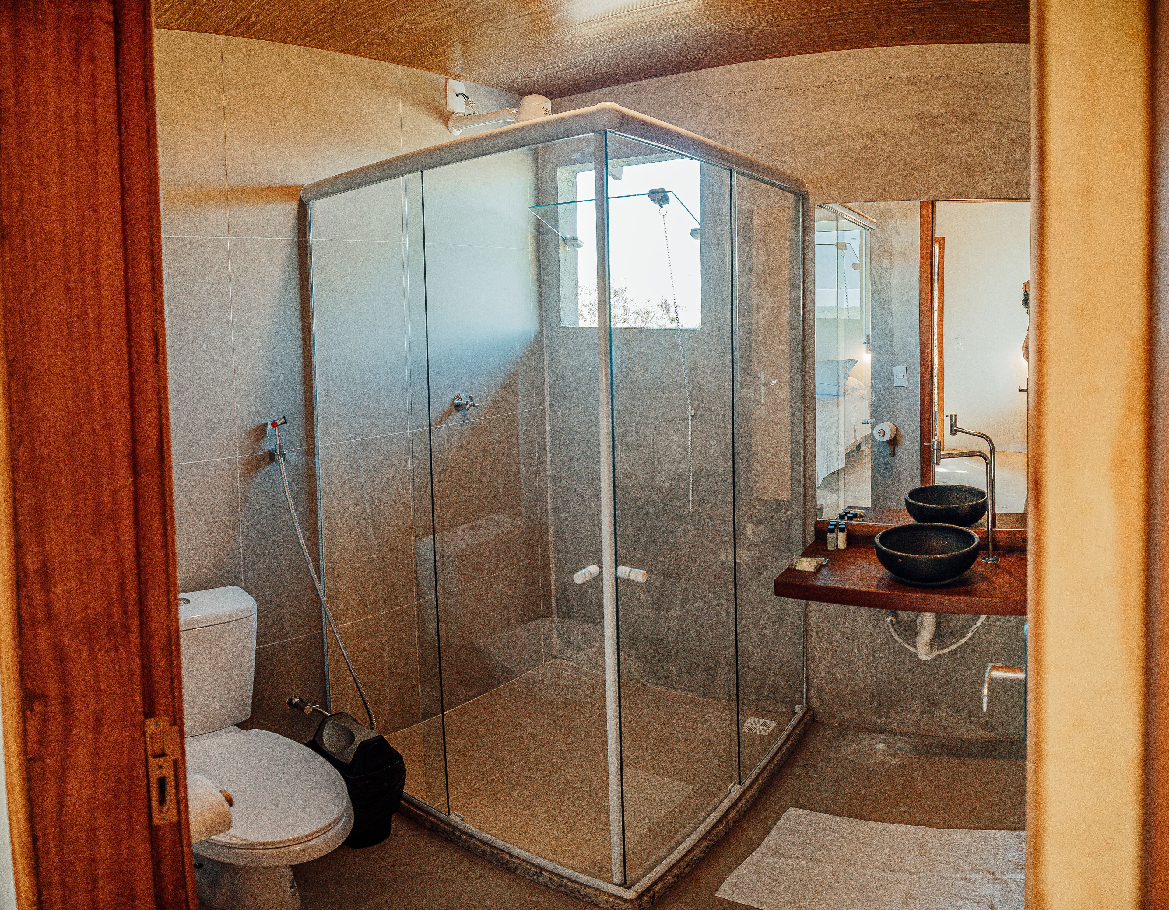 Un baño moderno con ducha envuelta en vidrio, inodoro y lavamanos con una pileta grande.