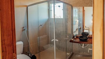A modern bathroom with a glass-enclosed shower, a toilet, and a sink with a large basin.