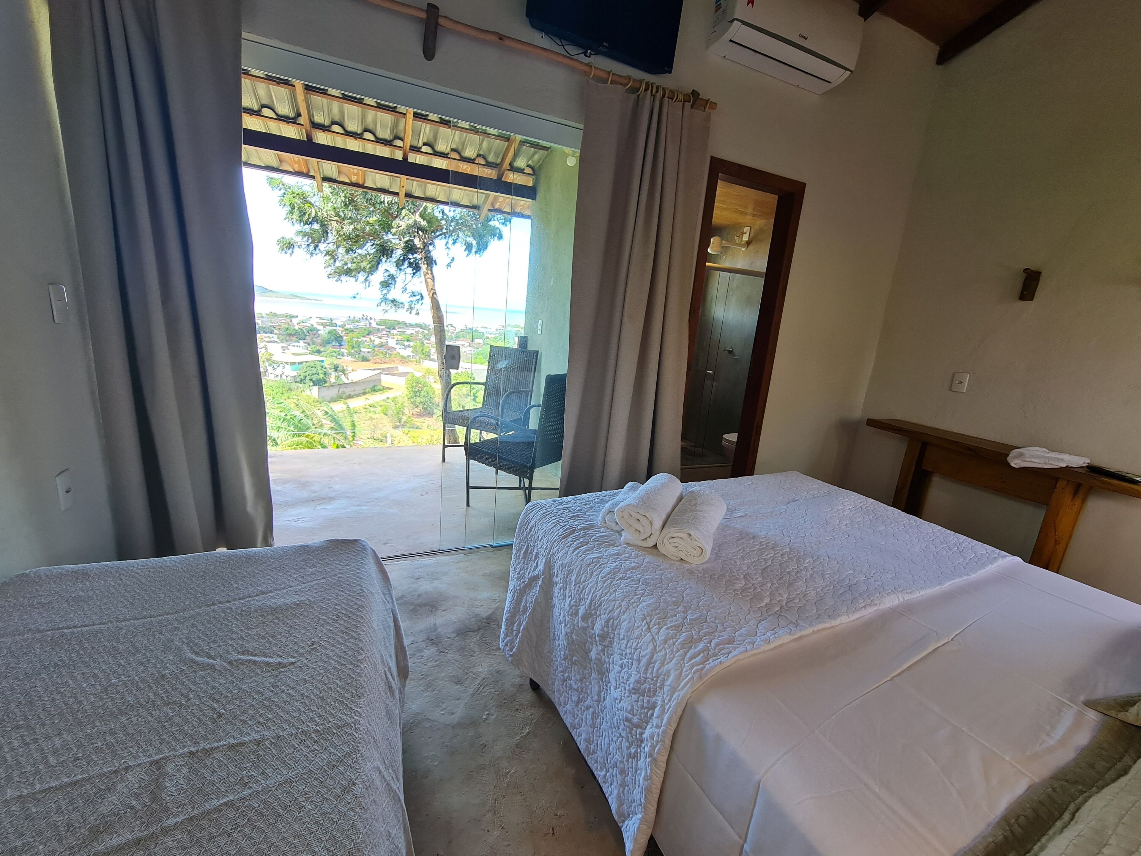 A room with two beds, a chair, and a view of the outdoors.
