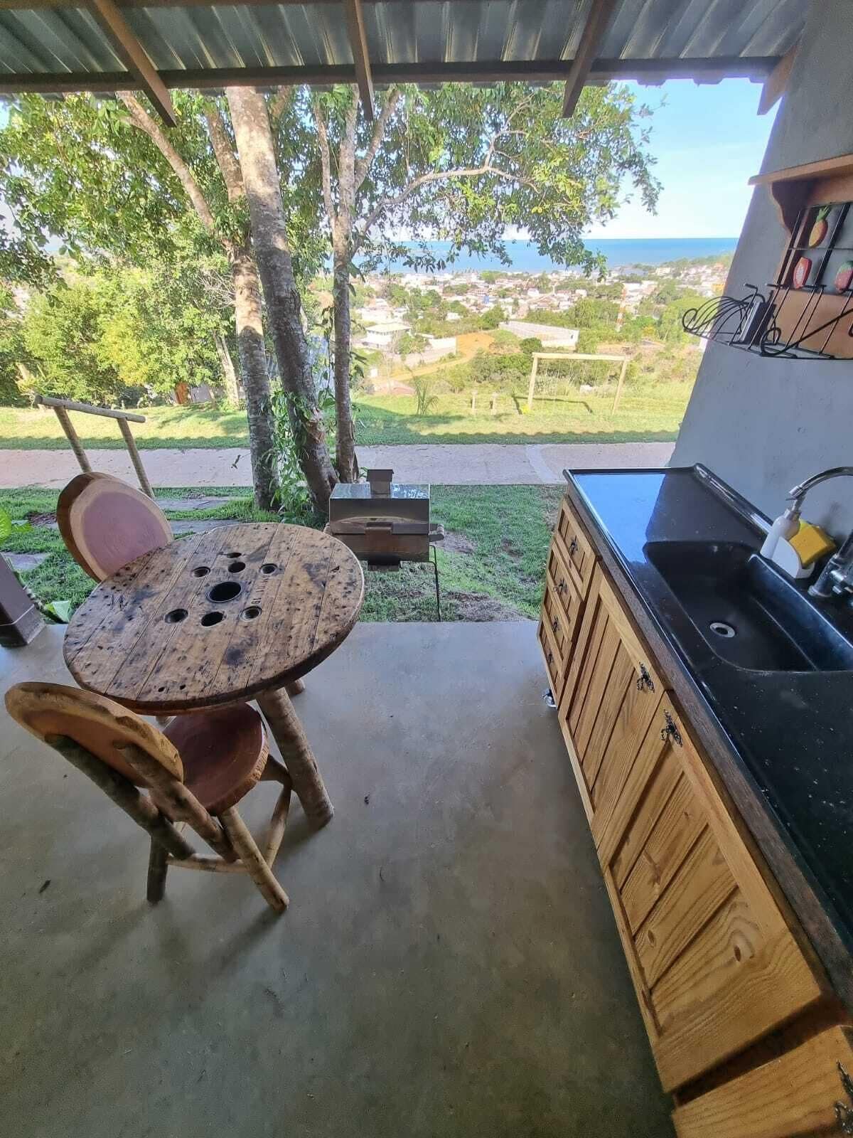 Un patio con una mesa y sillas de madera redonda, un lavabo y vistas a una carretera y follaje.