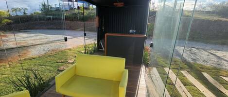 A modern outdoor seating area with a yellow sofa and a wooden deck.