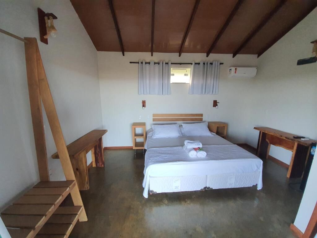 Een slaapkamer met een houten bed, een klein bureau, een nachtkastje en een houten trap.