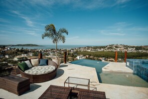 A rooftop infinity pool with wicker furniture and a view of the city.
