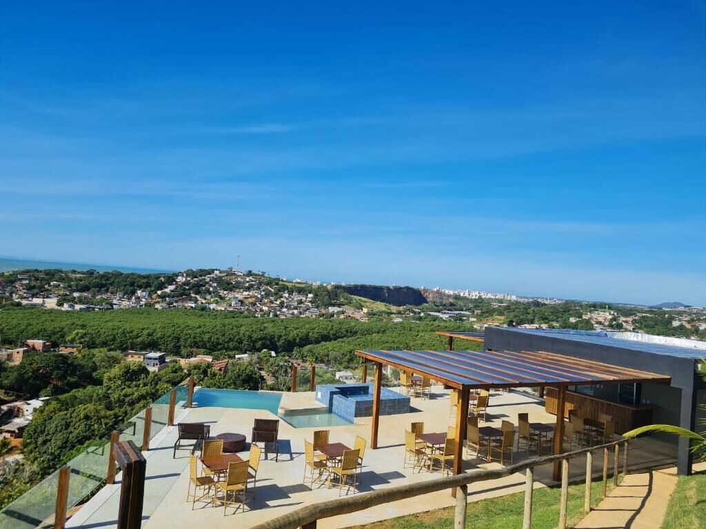 A rooftop terrace with a pool, outdoor seating, and a view of a coastal town.