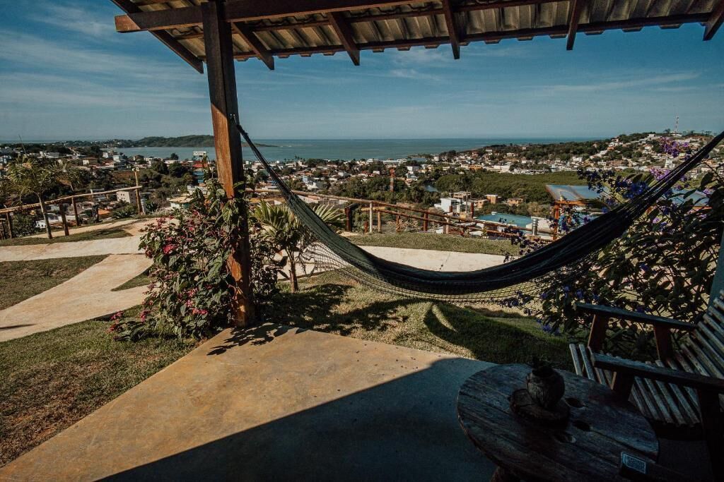 A hammock under a wooden pergola overlooking a coastal town.