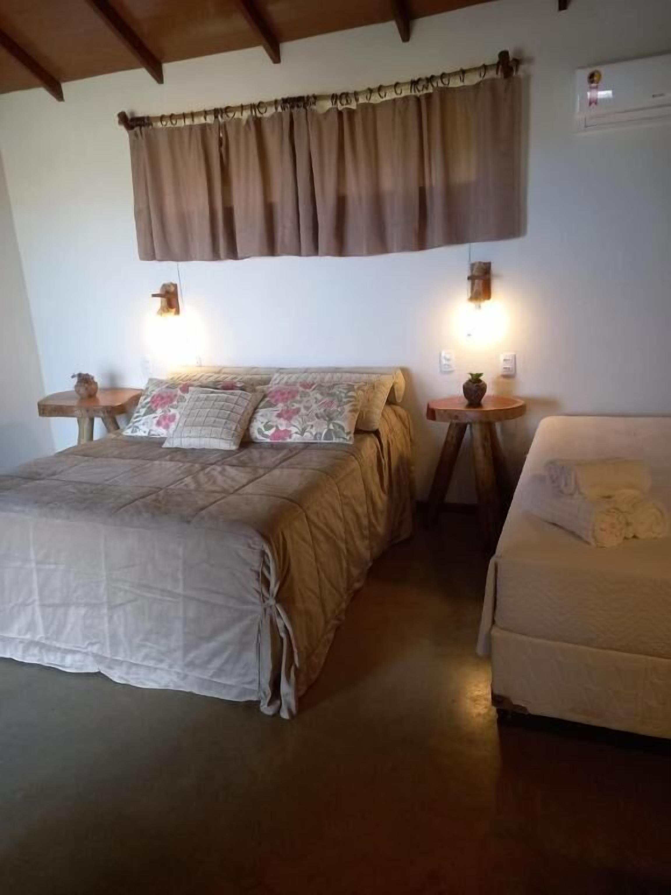 Un dormitorio con cama, mesita de noche, lámpara y una pequeña mesa con una planta.
