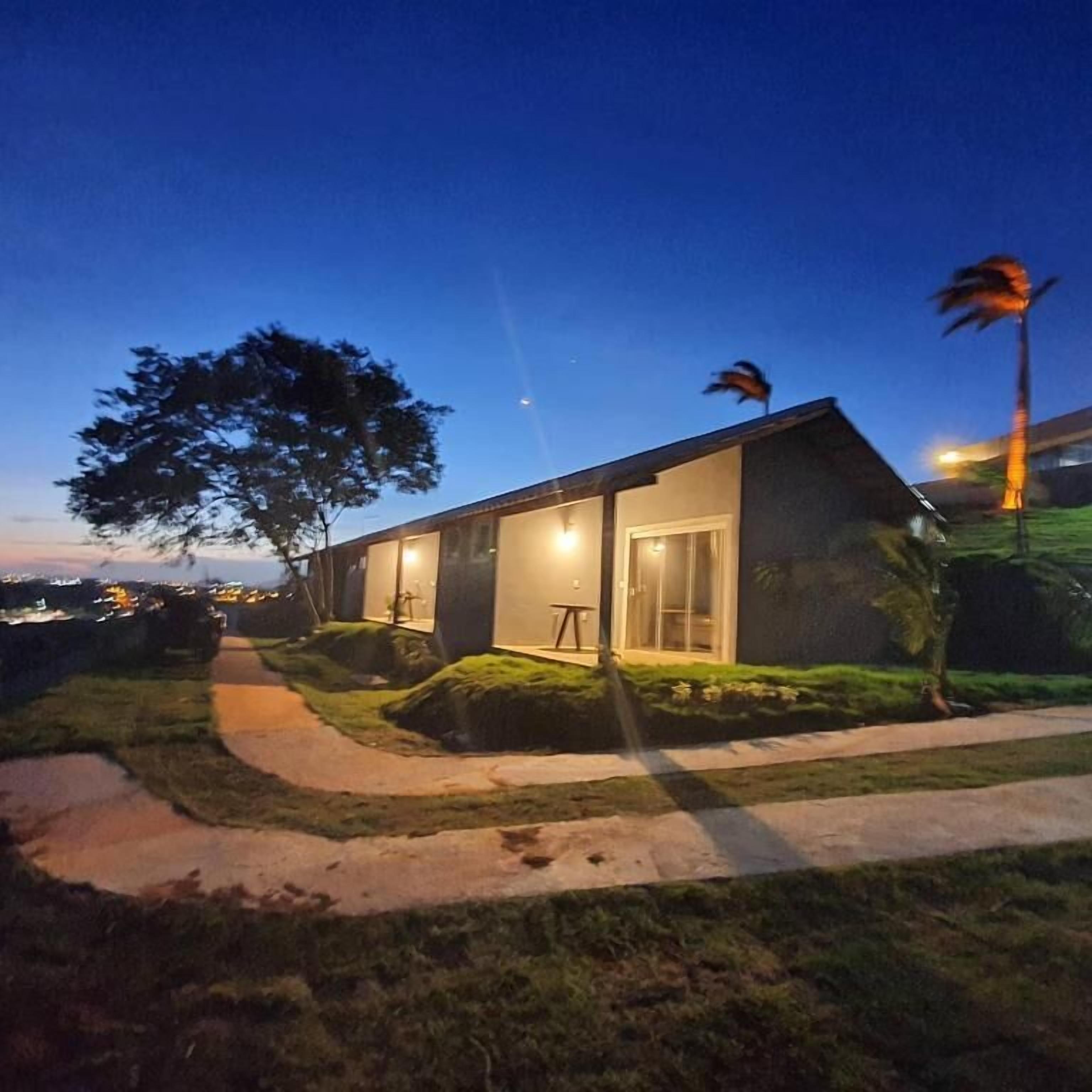 Una casa moderna con una porta di vetro, un piccolo patio e un albero nel giardino.