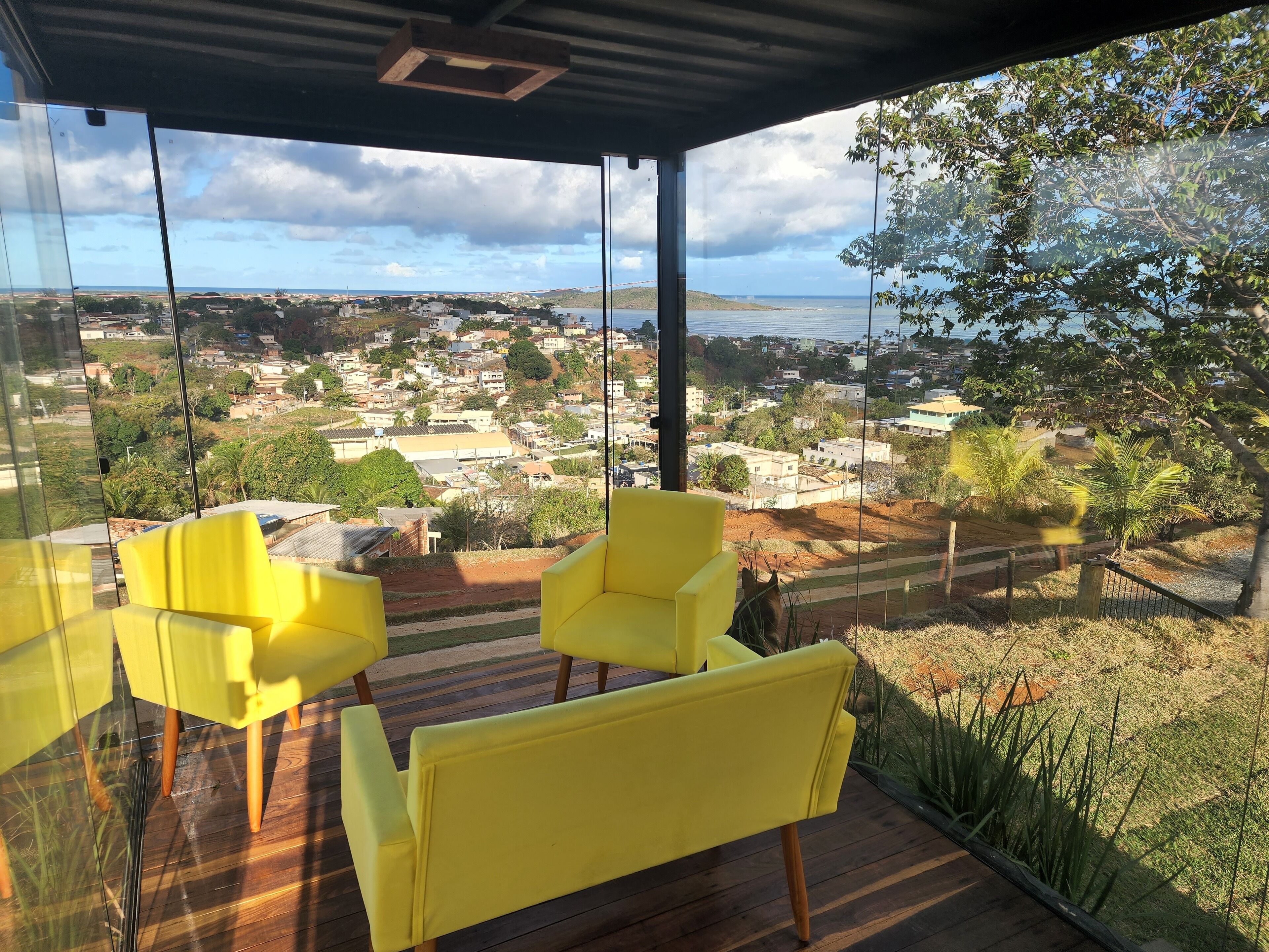 A modern room with large windows offering a view of a coastal town and the sea.