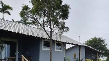 A two-story house with a tiled roof, a small garden, and a wooden staircase leading to the entrance.