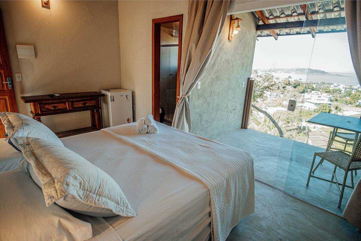 A hotel room with a bed, a table, and a view of the city.